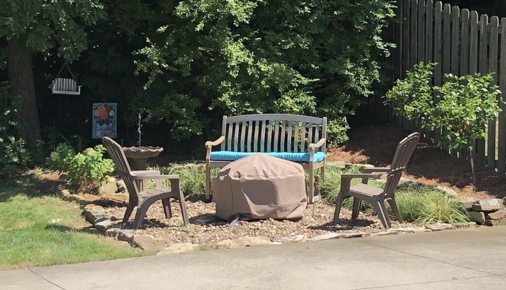 A gravel fire pit area is shown with a pair of plastic Adirondack chairs and a wooden bench seat.